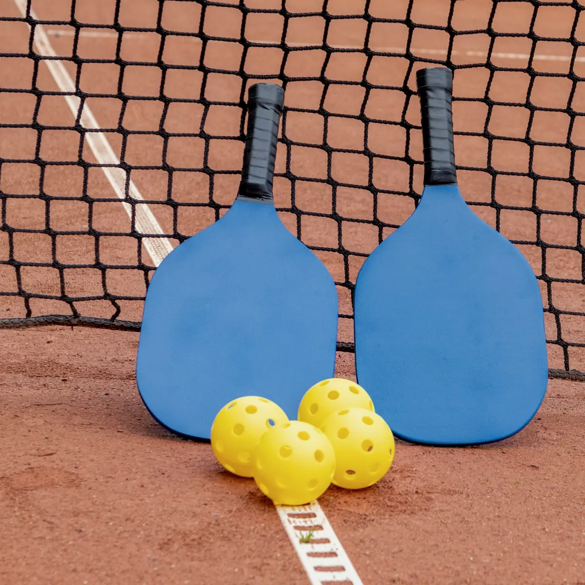 Pickleball paddles and balls at the net